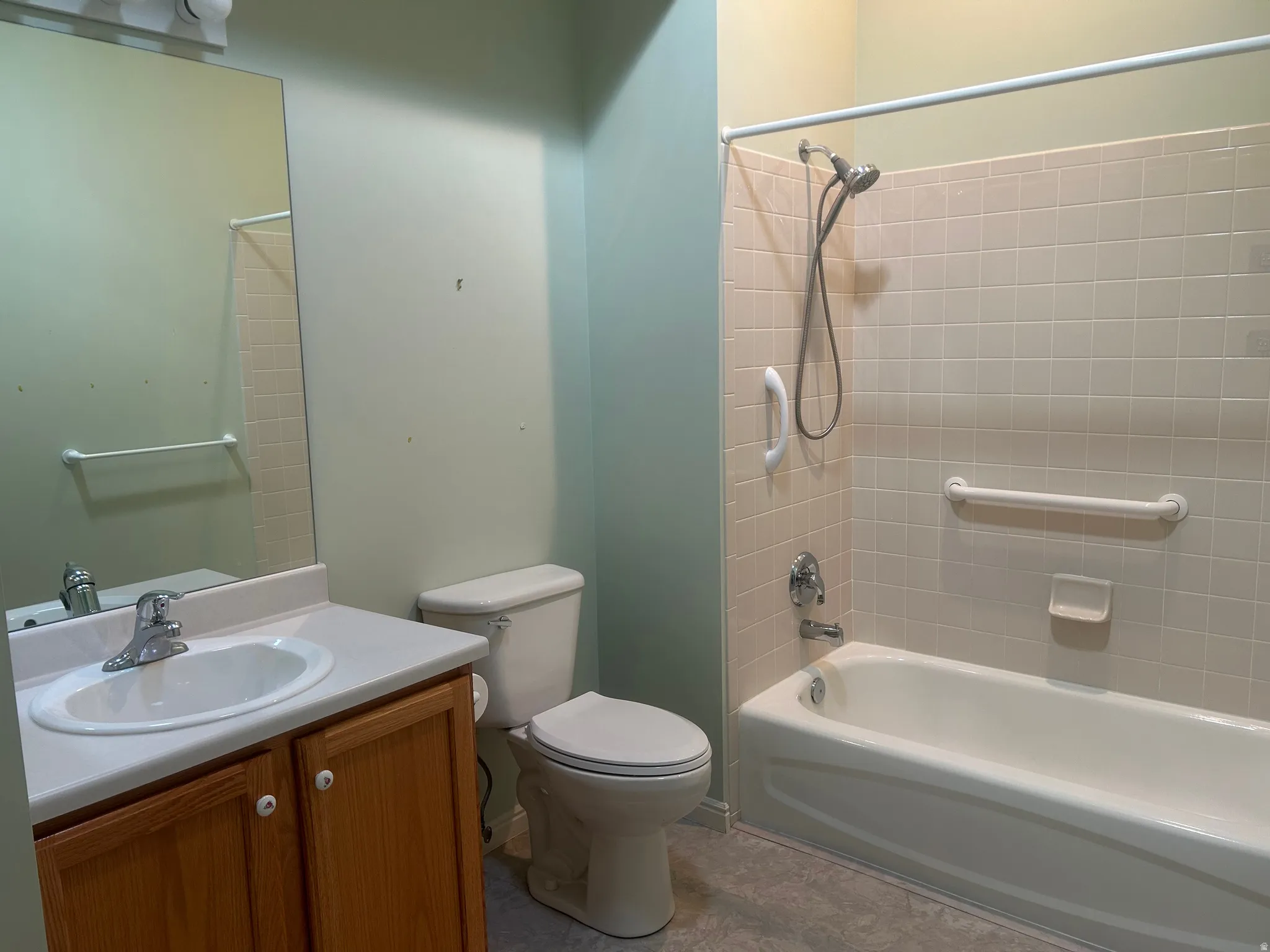 Bathroom featuring a bathtub with tiled surround, a toilet, and a vanity with an integrated sink