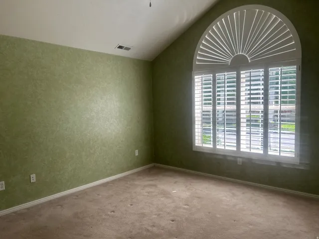 Primary bedroom with vaulted ceiling room featuring a large arched window with plantation shutters