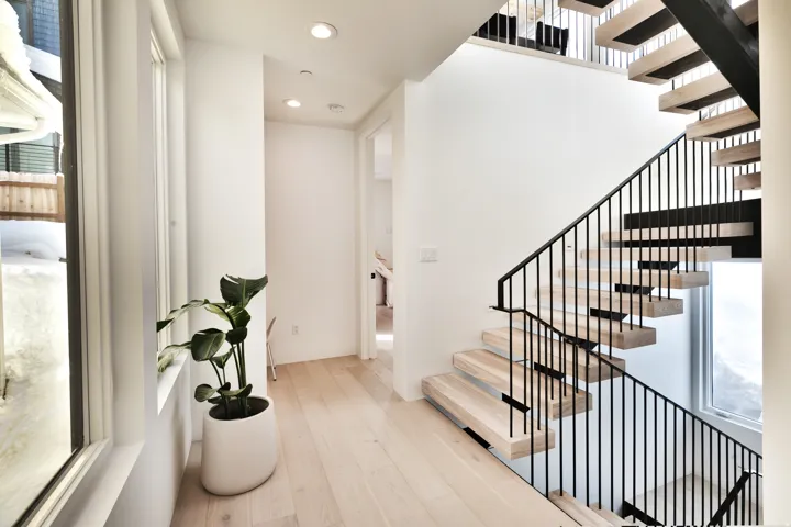 Modern open-tread staircase with black metal railings and light wood-finish treads