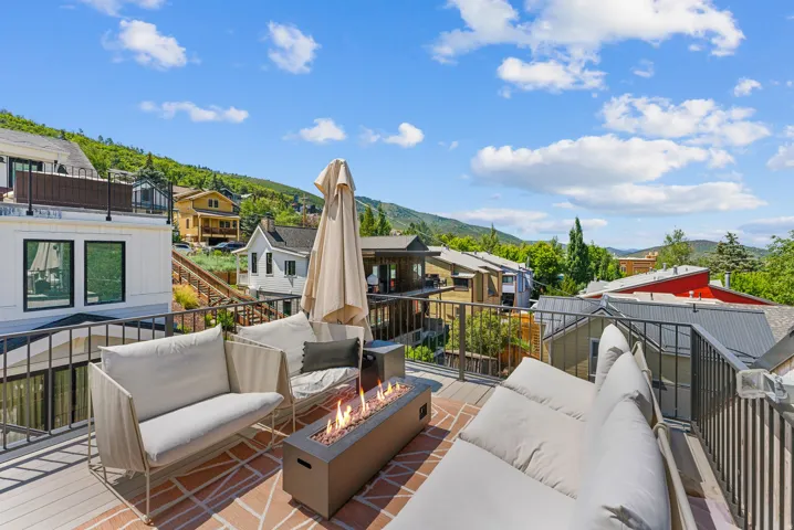 Rooftop deck featuring a built-in fire pit, metal railings, and a combination of wood-finish and patterned brick-style flooring