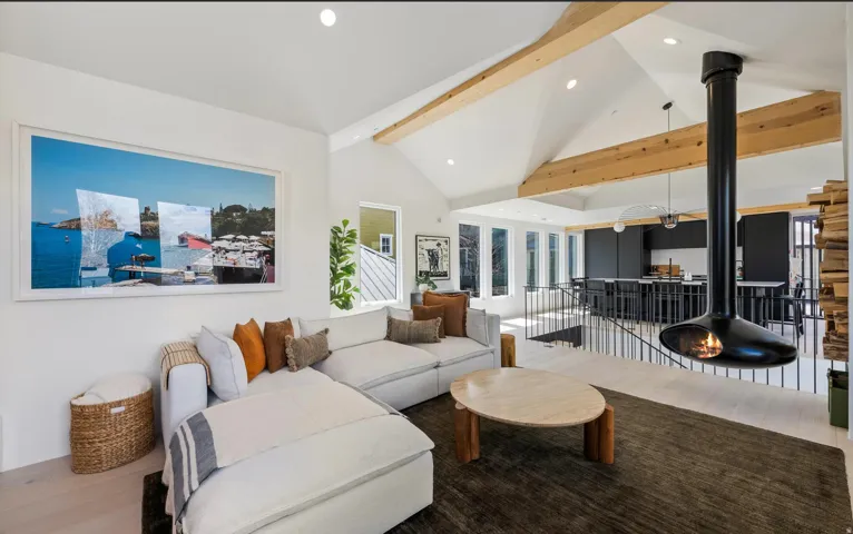 Living area featuring a vaulted ceiling with exposed wood beams, recessed lighting, and light wood-finish flooring