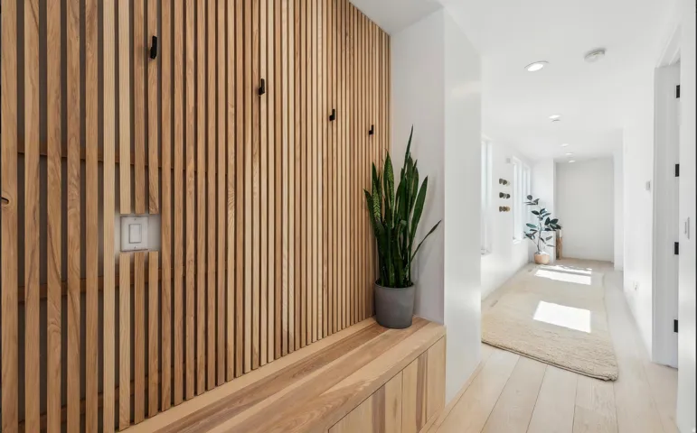 Entryway featuring a wood-slat accent wall with integrated coat hooks, a built-in wood bench, and light wood-finish flooring
