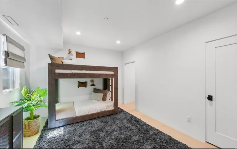 Spacious room featuring light wood-finish flooring and recessed lighting
