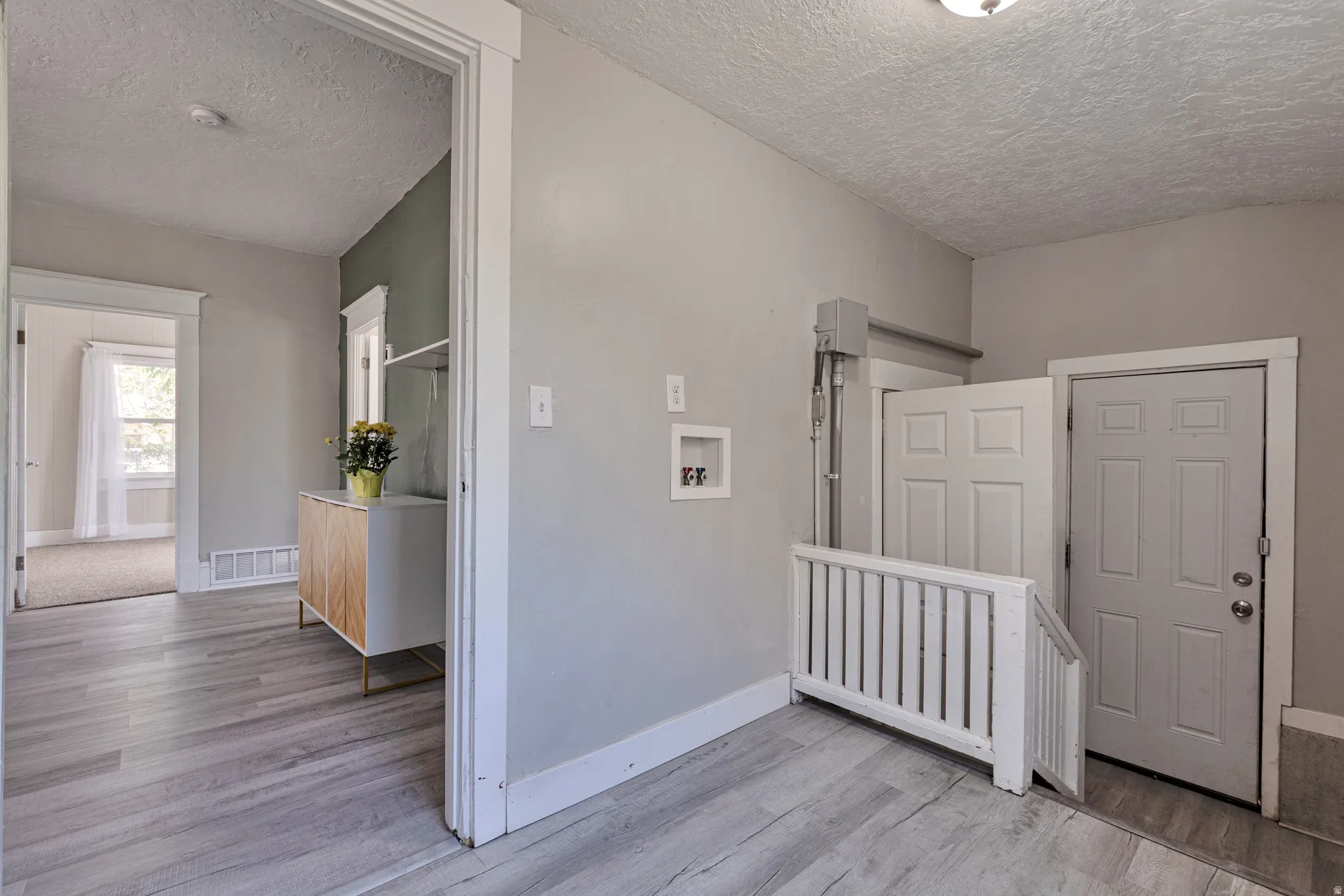 Wood-finish flooring throughout, featuring light gray walls, white trim, and a utility area with washer/dryer hookups
