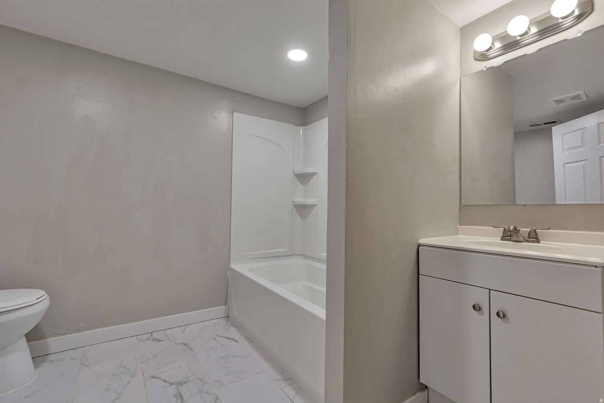 Contemporary bathroom featuring a white vanity with integrated sink, chrome faucet, and mirrored medicine cabinet