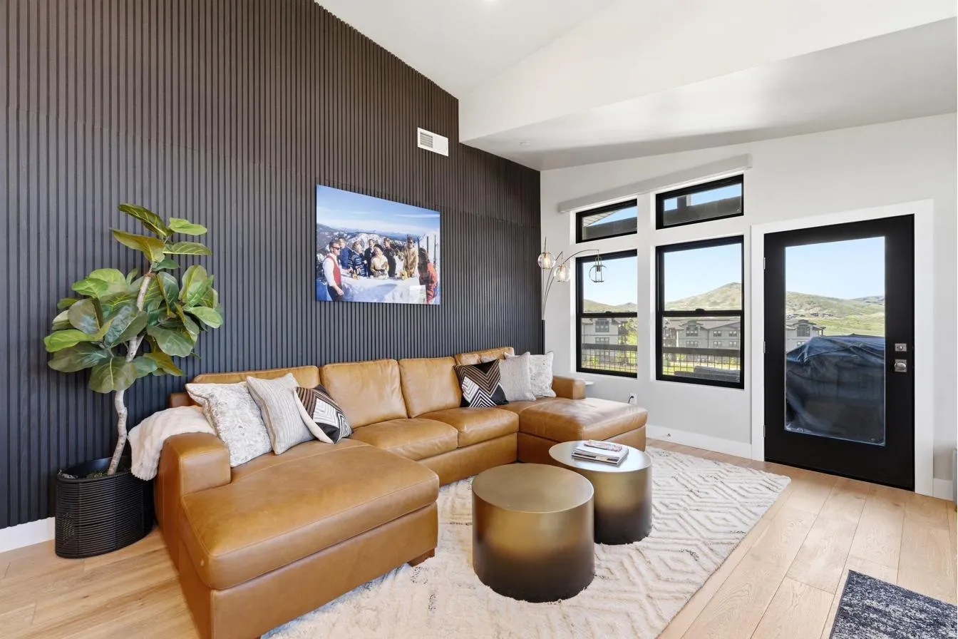 Spacious living area featuring a vaulted ceiling and a slatted accent wall