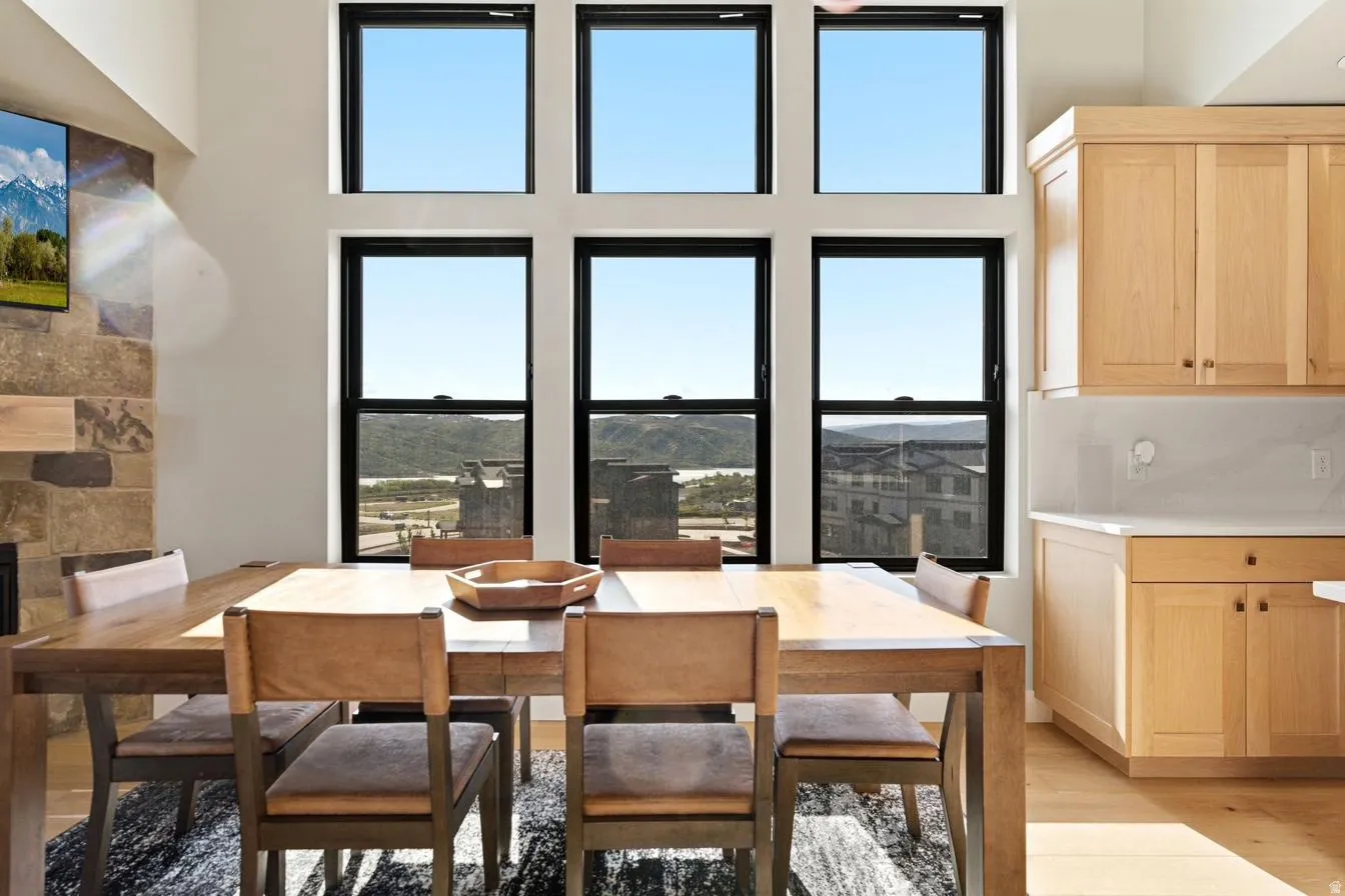 Great room featuring a floor-to-ceiling window array, stone-faced fireplace, and light wood flooring