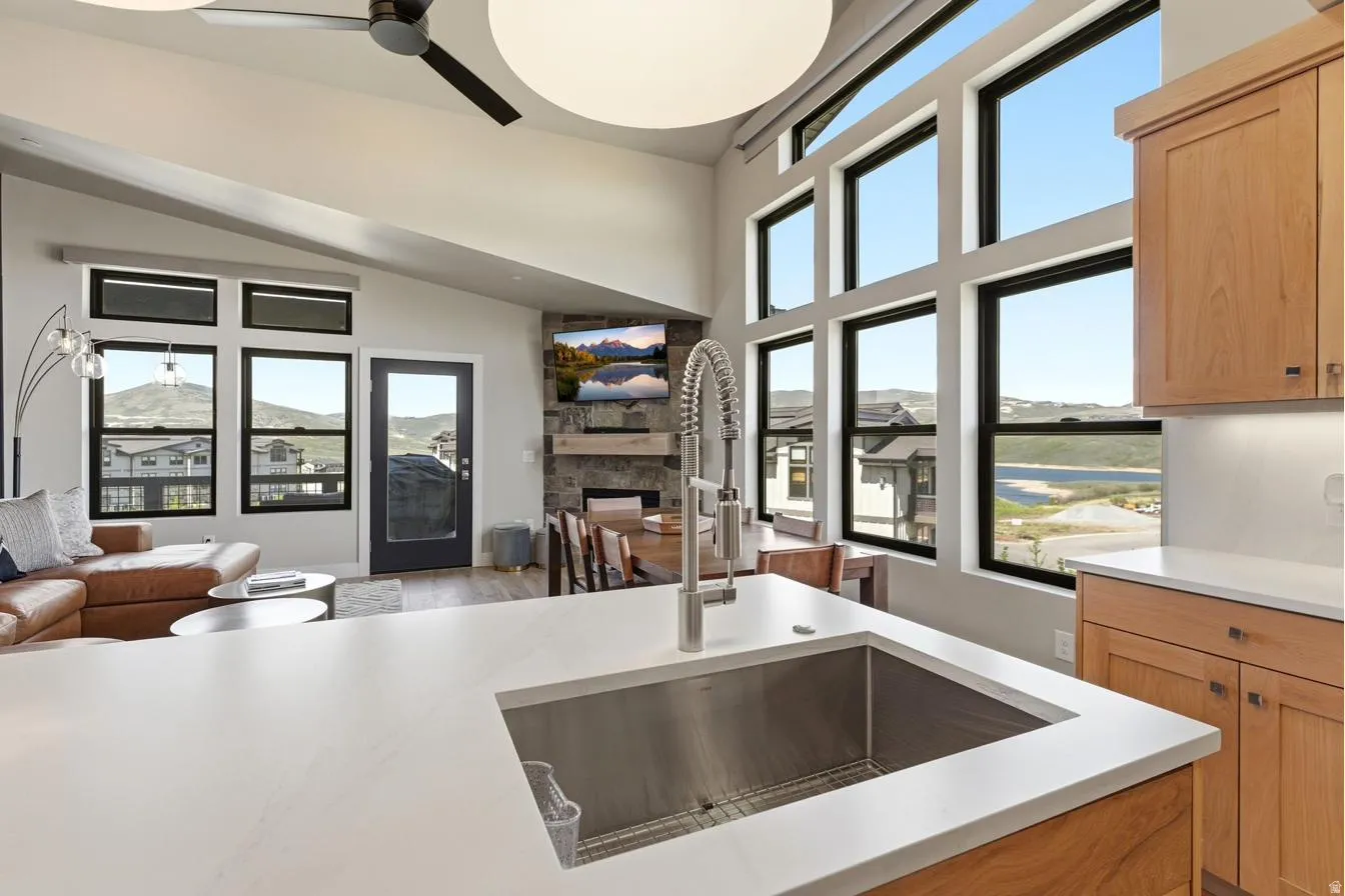 Kitchen island featuring a stainless steel sink with a high-arch faucet, white countertop, and wood-finish cabinetry
