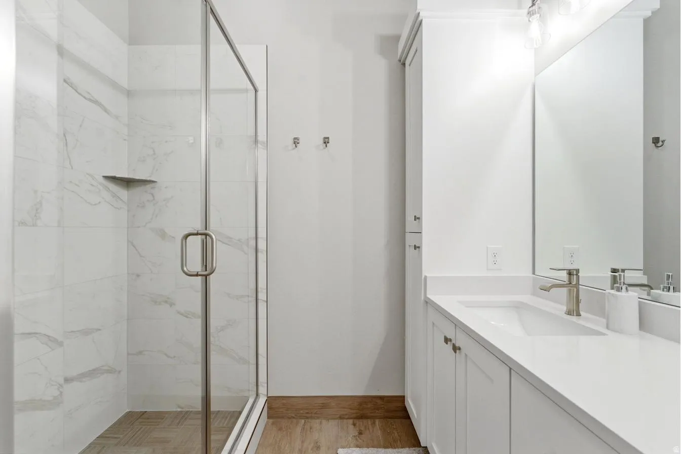 Shower with glass enclosure and white marble-patterned tile