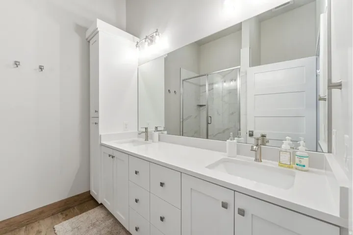 Bathroom featuring a dual vanity with white cabinetry, integrated sinks, and brushed nickel hardware