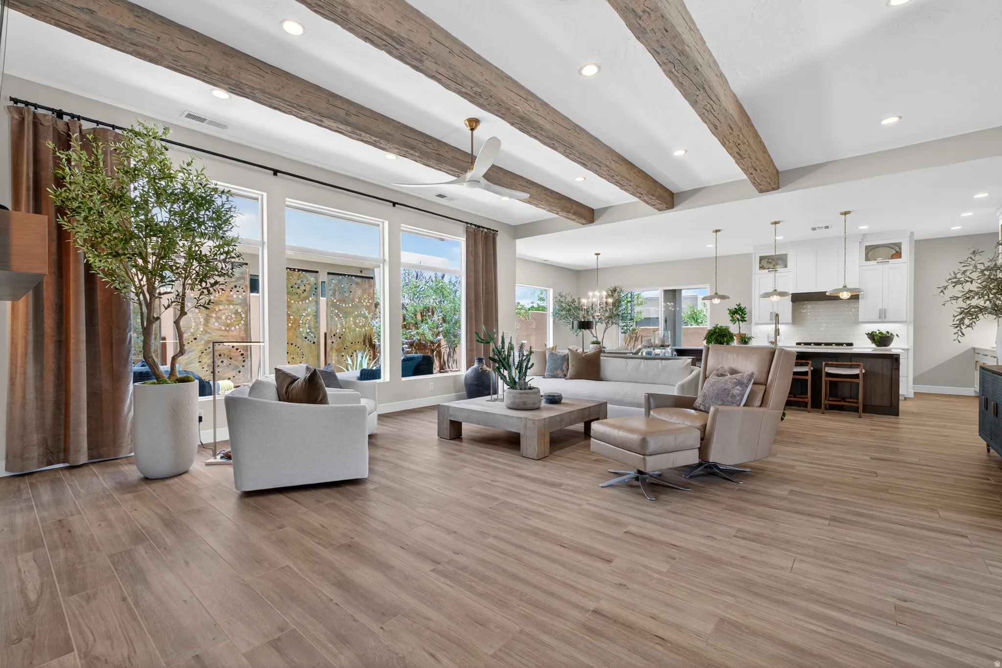 Open-concept living area featuring wood-finish plank flooring and exposed wood ceiling beams