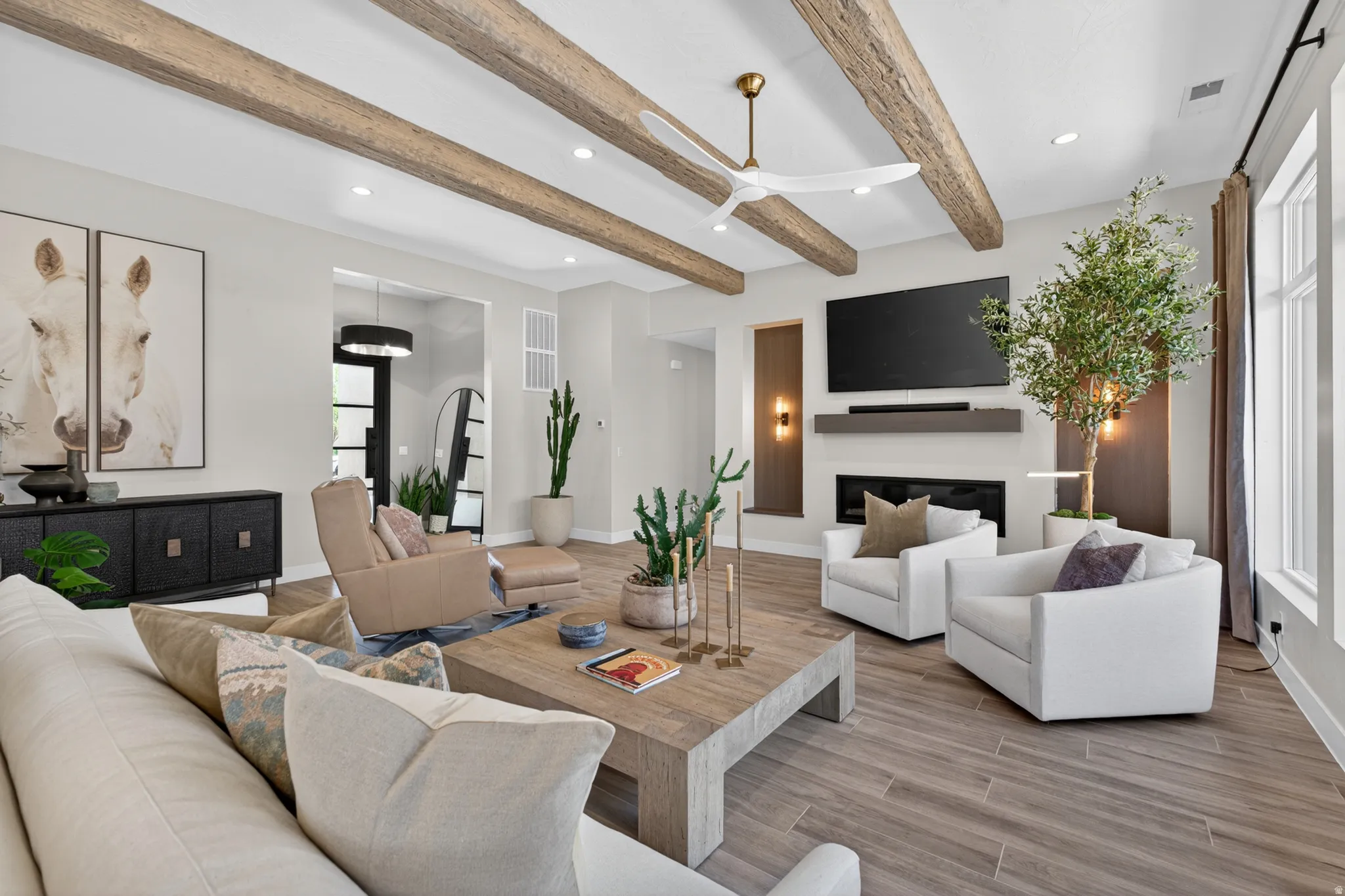 Spacious living area featuring exposed wood-finish ceiling beams, wood-finish tile flooring, a contemporary fireplace with a built-in mantel, and recessed lighting