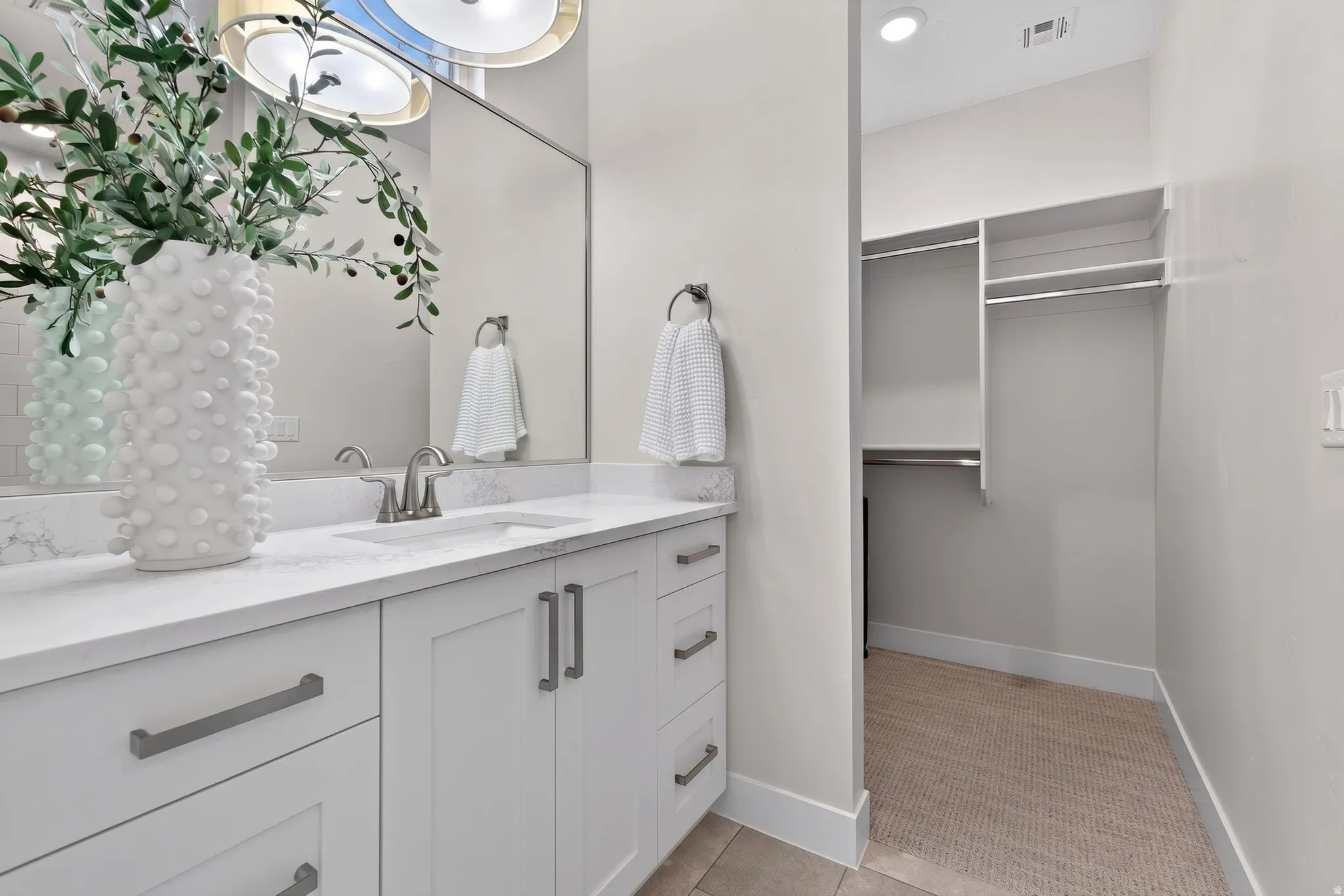 Bathroom vanity featuring a single sink, light-toned countertop, and white cabinetry with brushed nickel hardware