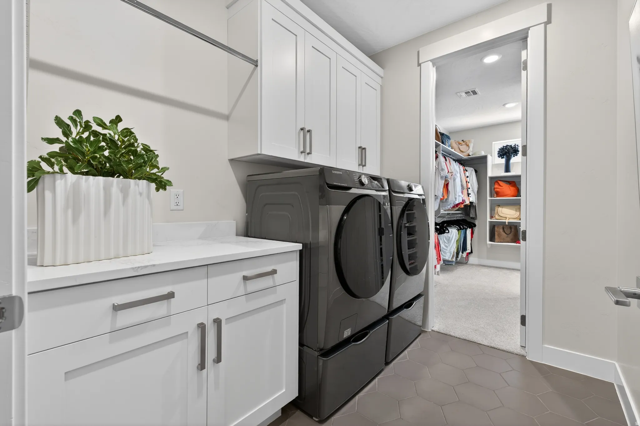 Dedicated laundry area featuring white shaker-style cabinetry, a white countertop, and hexagonal floor tiling
