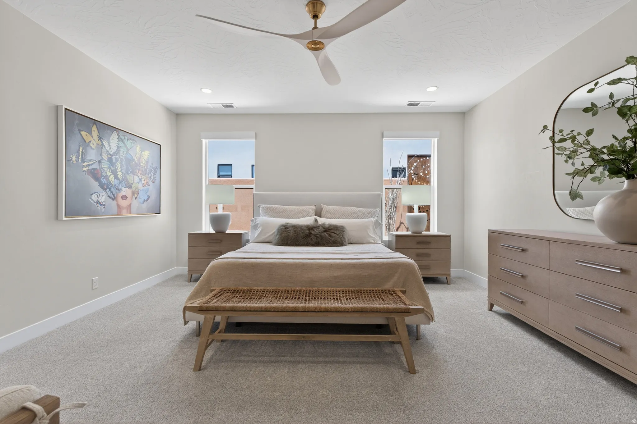 Spacious bedroom featuring plush carpeting, a ceiling fan with integrated lighting, recessed lighting, and two windows providing natural illumination