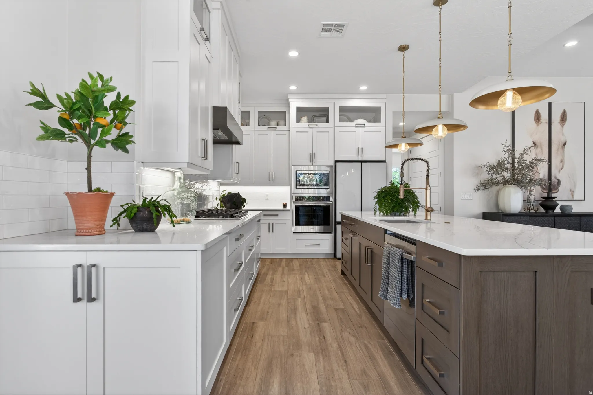 Modern kitchen featuring a large central island with a built-in sink and three pendant lights