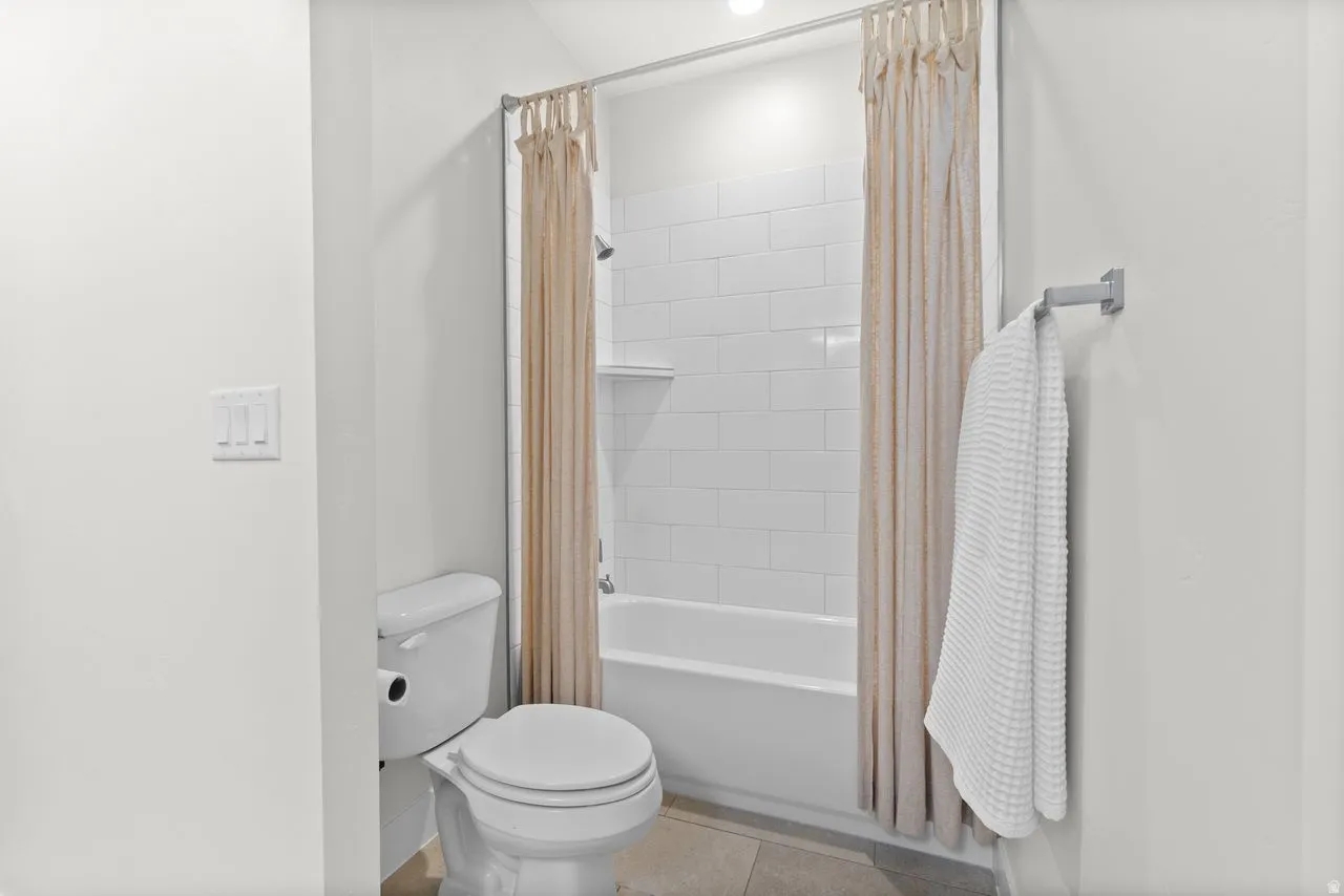 Bathroom featuring a white bathtub, white subway tile surround, and a white toilet