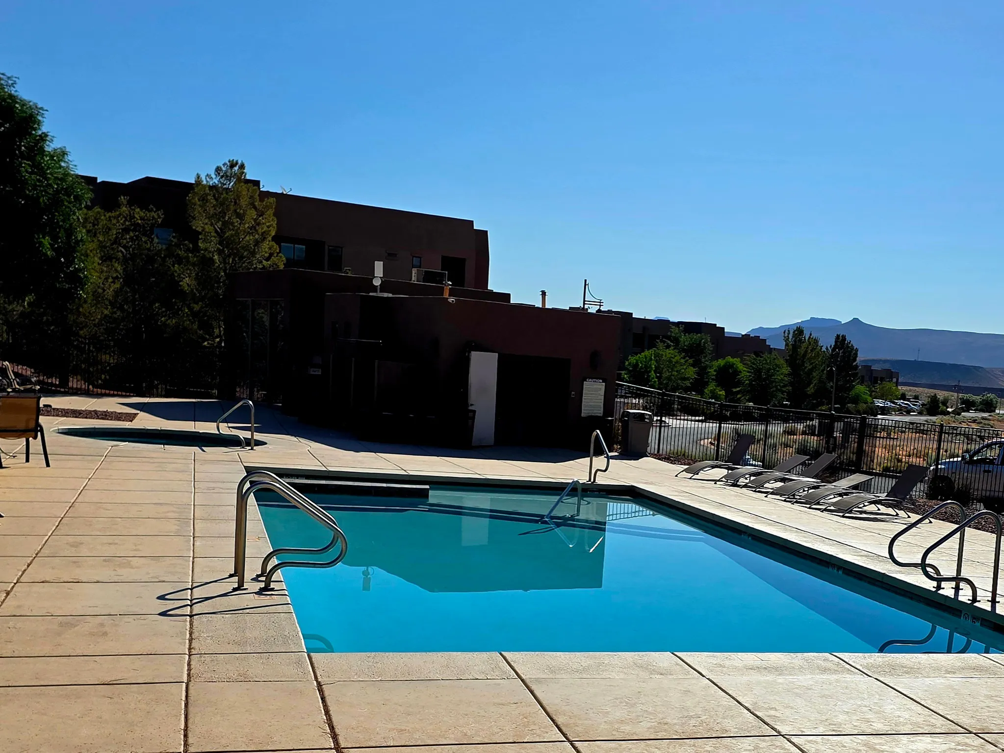Rectangular swimming pool with integrated steps and handrails, surrounded by a concrete deck