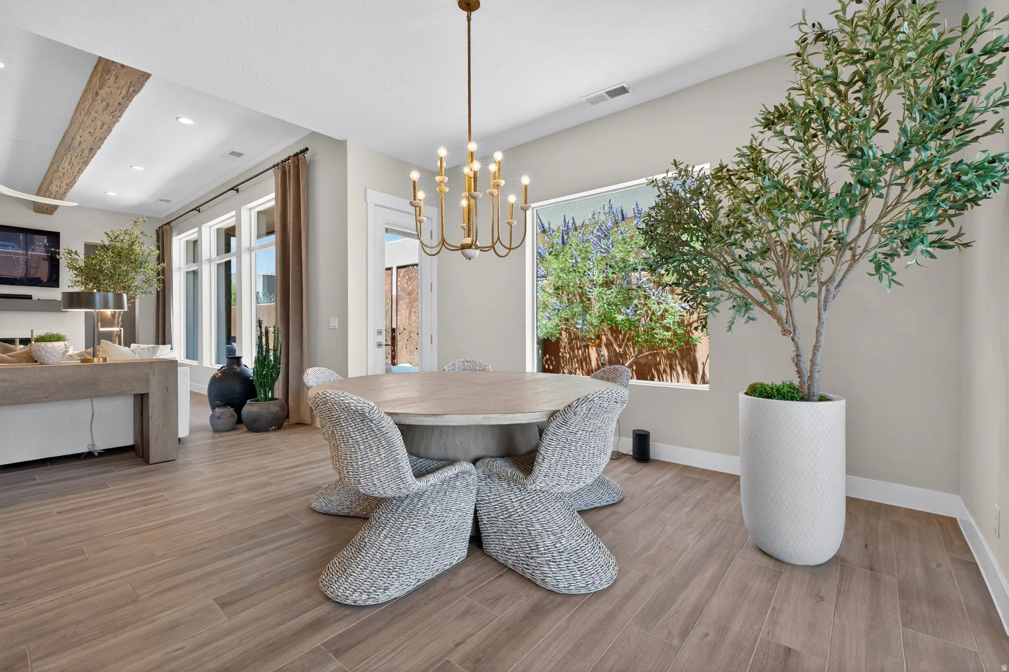 Open-concept dining area featuring wood-finish flooring and a brass chandelier