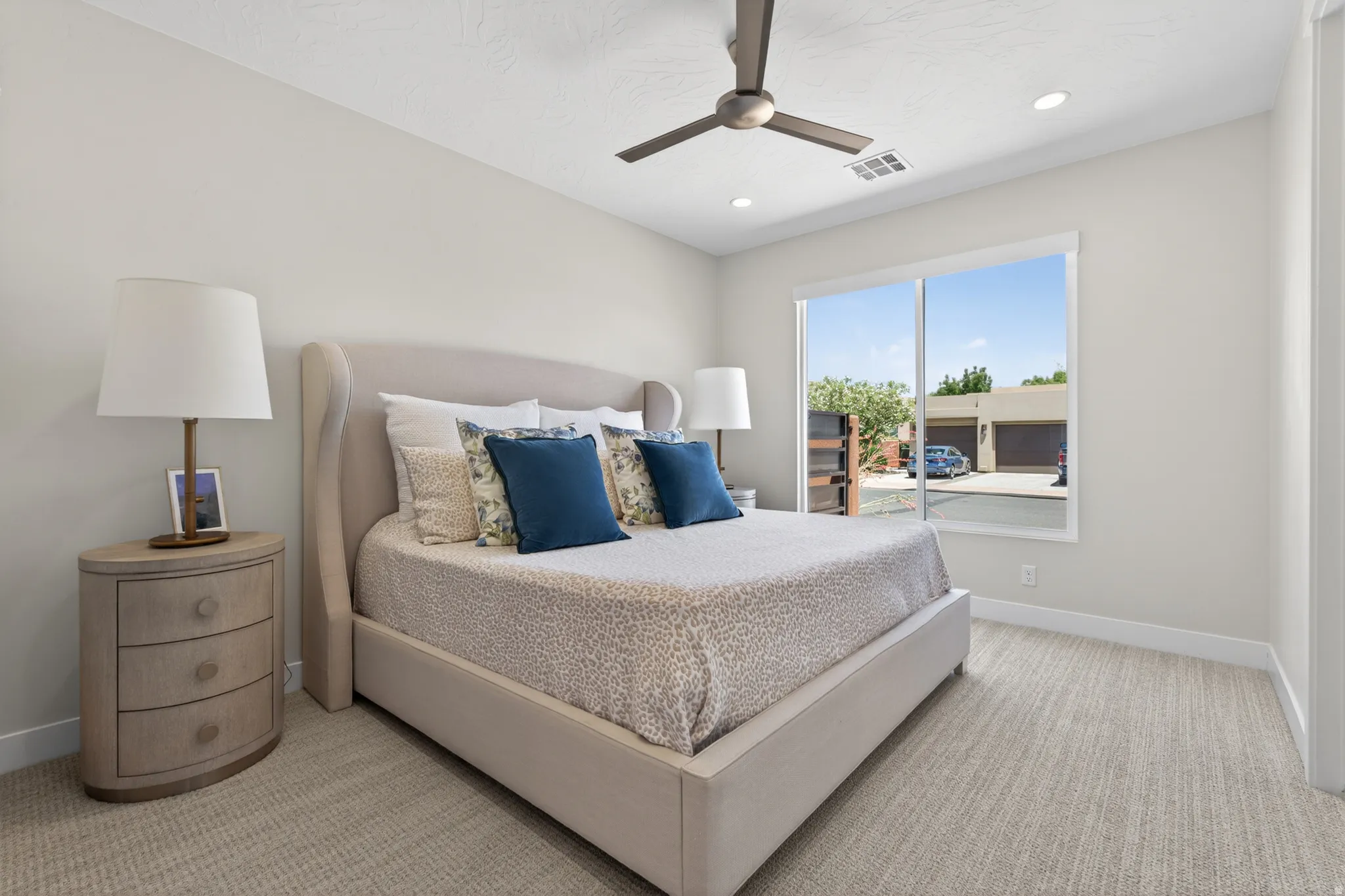 Neutral-toned bedroom featuring wall-to-wall carpeting, recessed lighting, and a contemporary ceiling fan