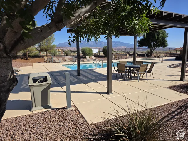 Outdoor pool area featuring a built-in spa, a metal pergola, and concrete paver decking