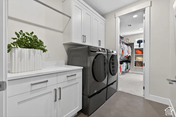 Dedicated laundry area featuring white shaker-style cabinetry, a white countertop, and hexagonal floor tiling