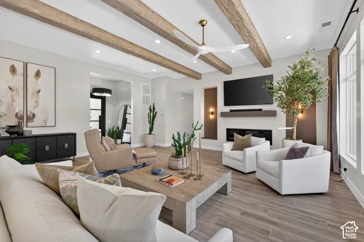 Spacious living area featuring exposed wood-finish ceiling beams, wood-finish tile flooring, a contemporary fireplace with a built-in mantel, and recessed lighting
