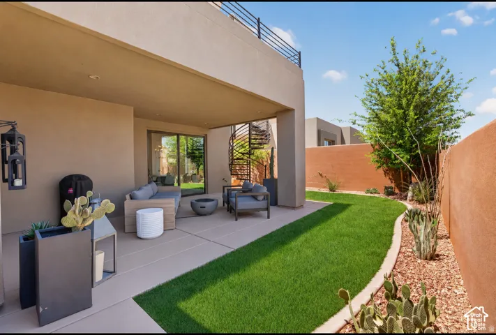 Expansive outdoor living area featuring a covered patio, spiral staircase to an upper balcony, and a manicured lawn