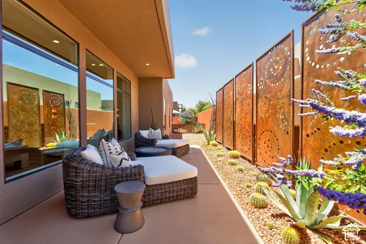 Expansive exterior patio #2 featuring a concrete surface, a decorative metal screen wall, a gravel xeriscape with cacti and succulents, and large picture windows