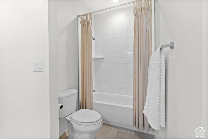 Bathroom featuring a white bathtub, white subway tile surround, and a white toilet