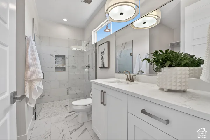 Bathroom featuring a single vanity with stone countertop, white cabinetry, and brushed nickel hardware