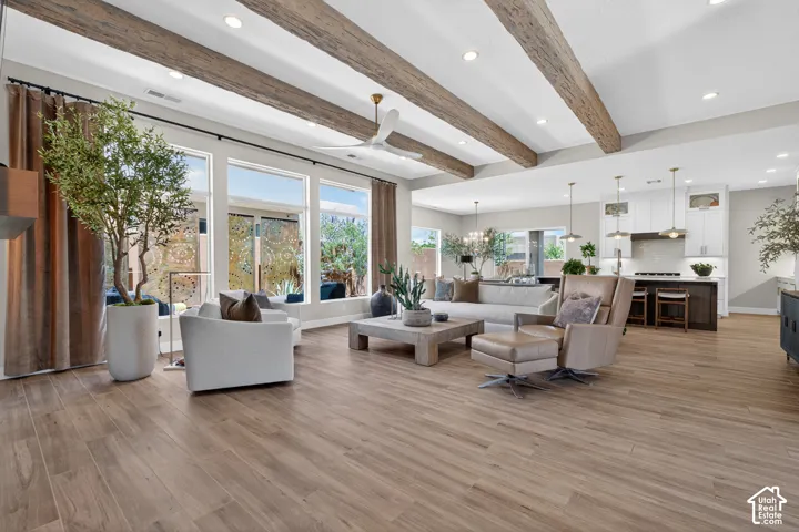 Open-concept living area featuring wood-finish plank flooring and exposed wood ceiling beams