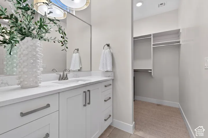 Bathroom vanity featuring a single sink, light-toned countertop, and white cabinetry with brushed nickel hardware