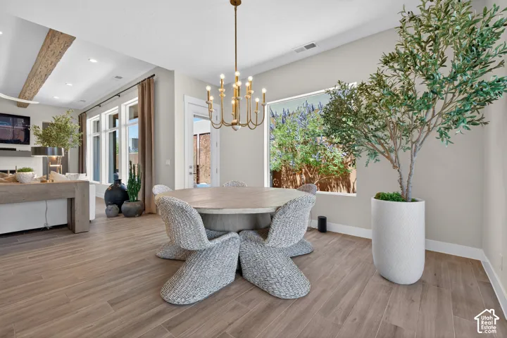 Open-concept dining area featuring wood-finish flooring and a brass chandelier