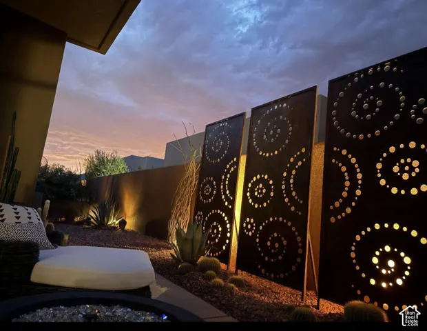 Architectural metal screens with decorative cutouts, landscape lighting, natural stone ground cover, and desert-adapted plants