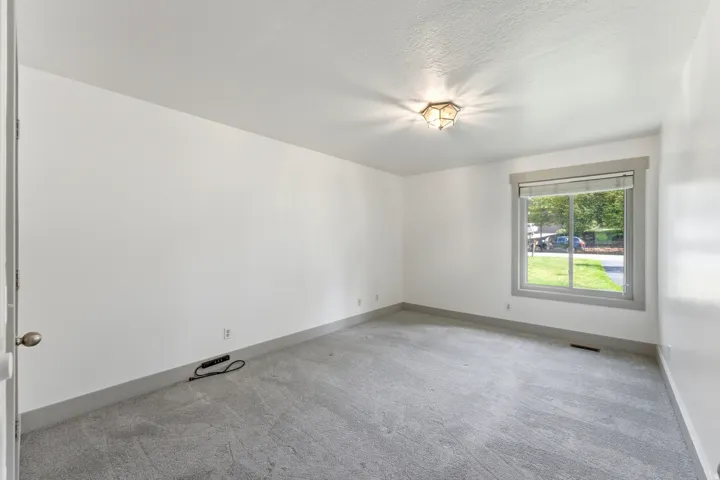 Spacious room featuring light gray carpeting and white painted walls