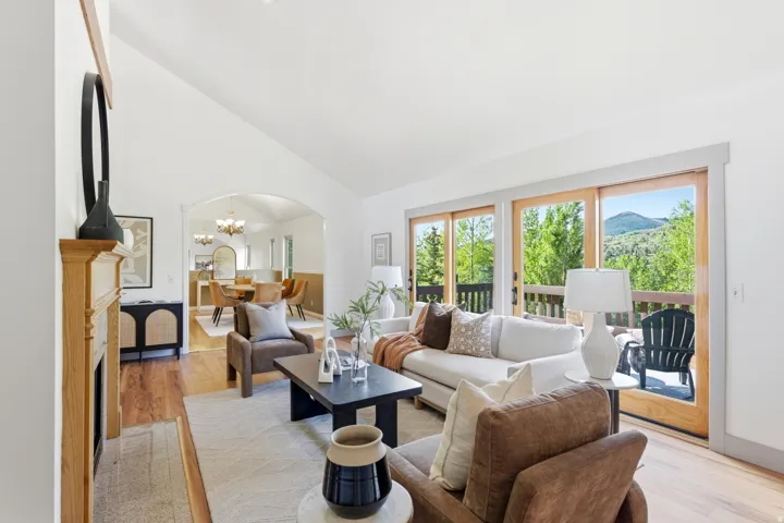 Living area featuring a vaulted ceiling, wood-finish flooring, and a decorative fireplace with a wood mantle