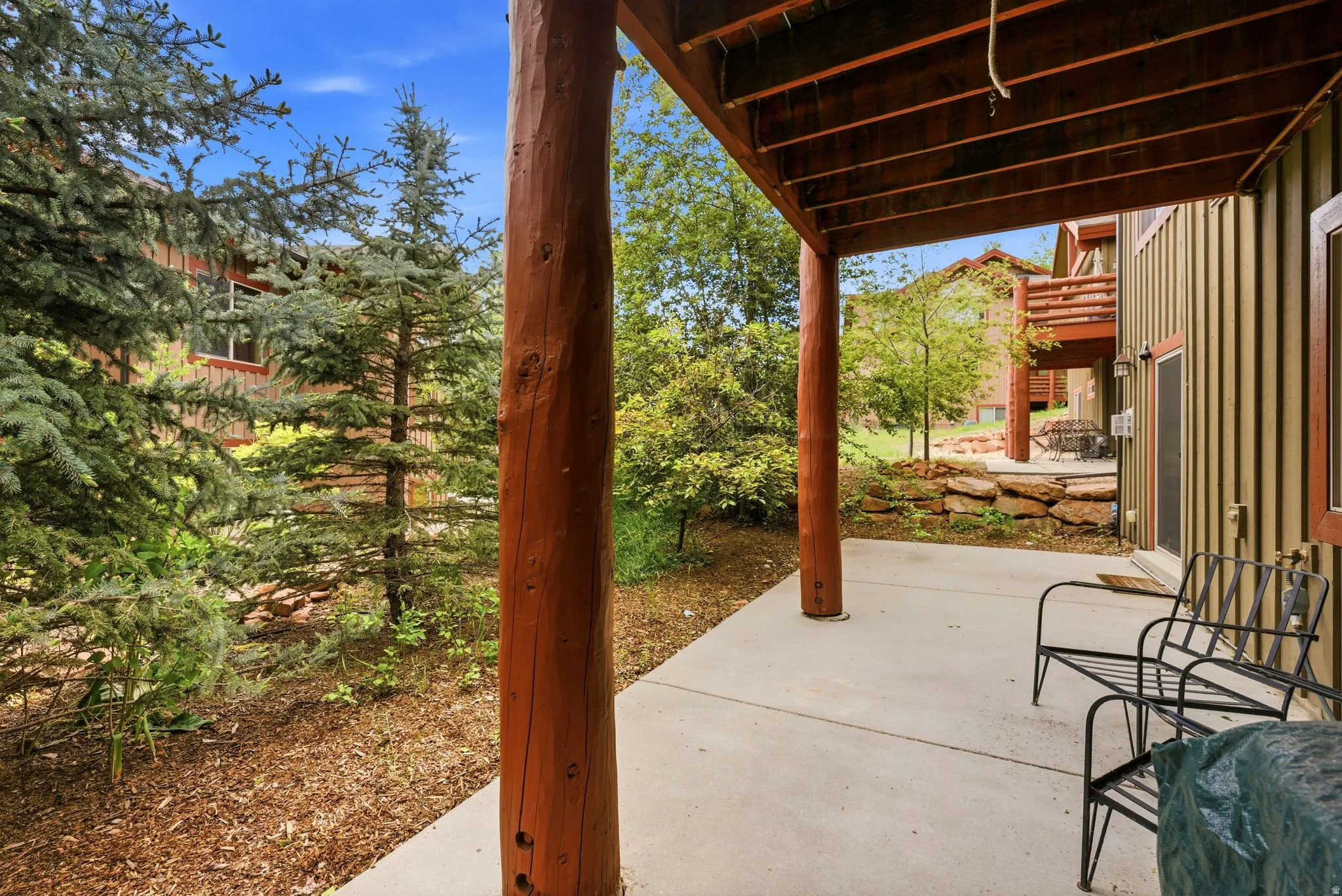 Ground-level patio featuring a concrete surface and a wood-beamed overhead structure