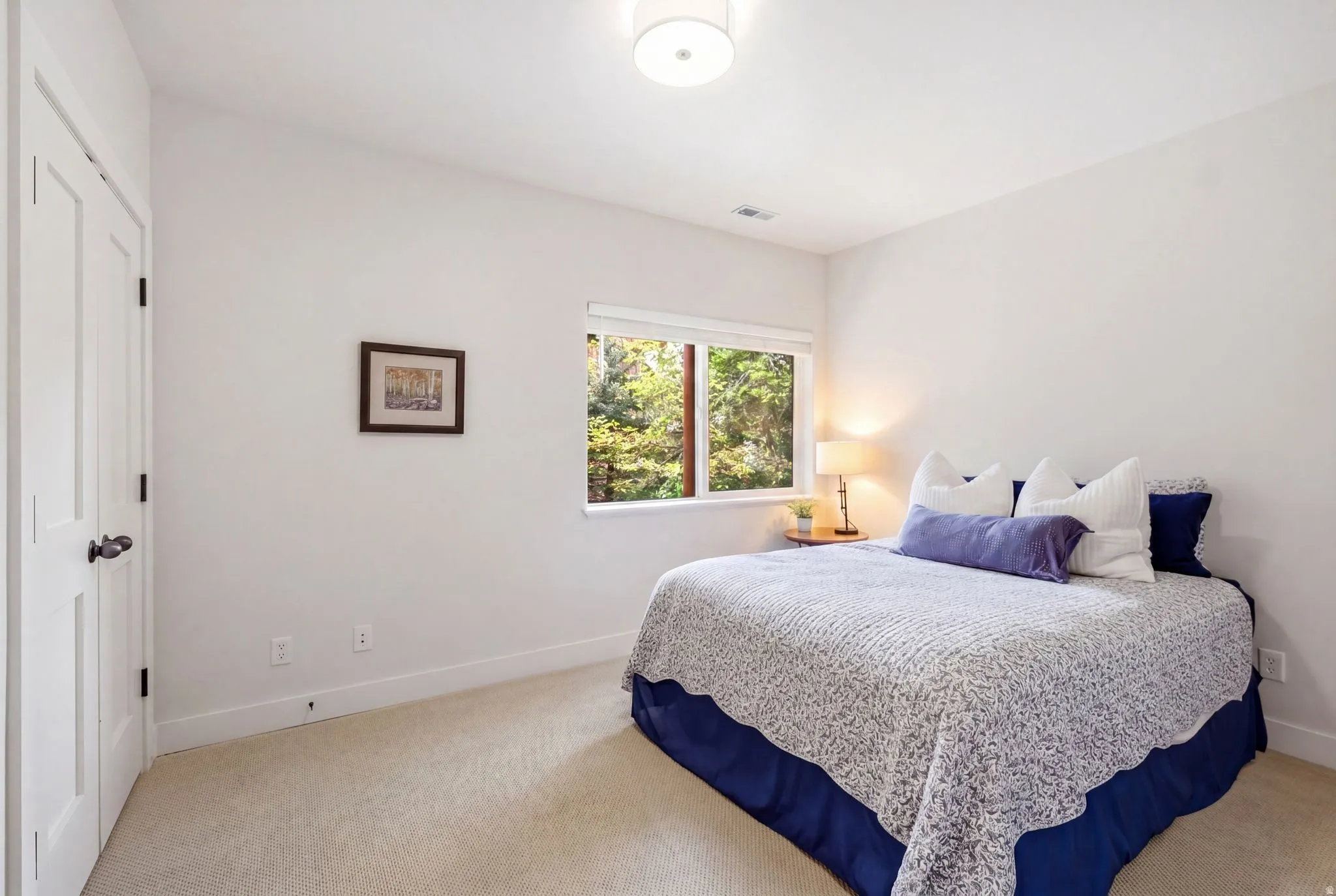 White interior walls with a single window overlooking lush greenery