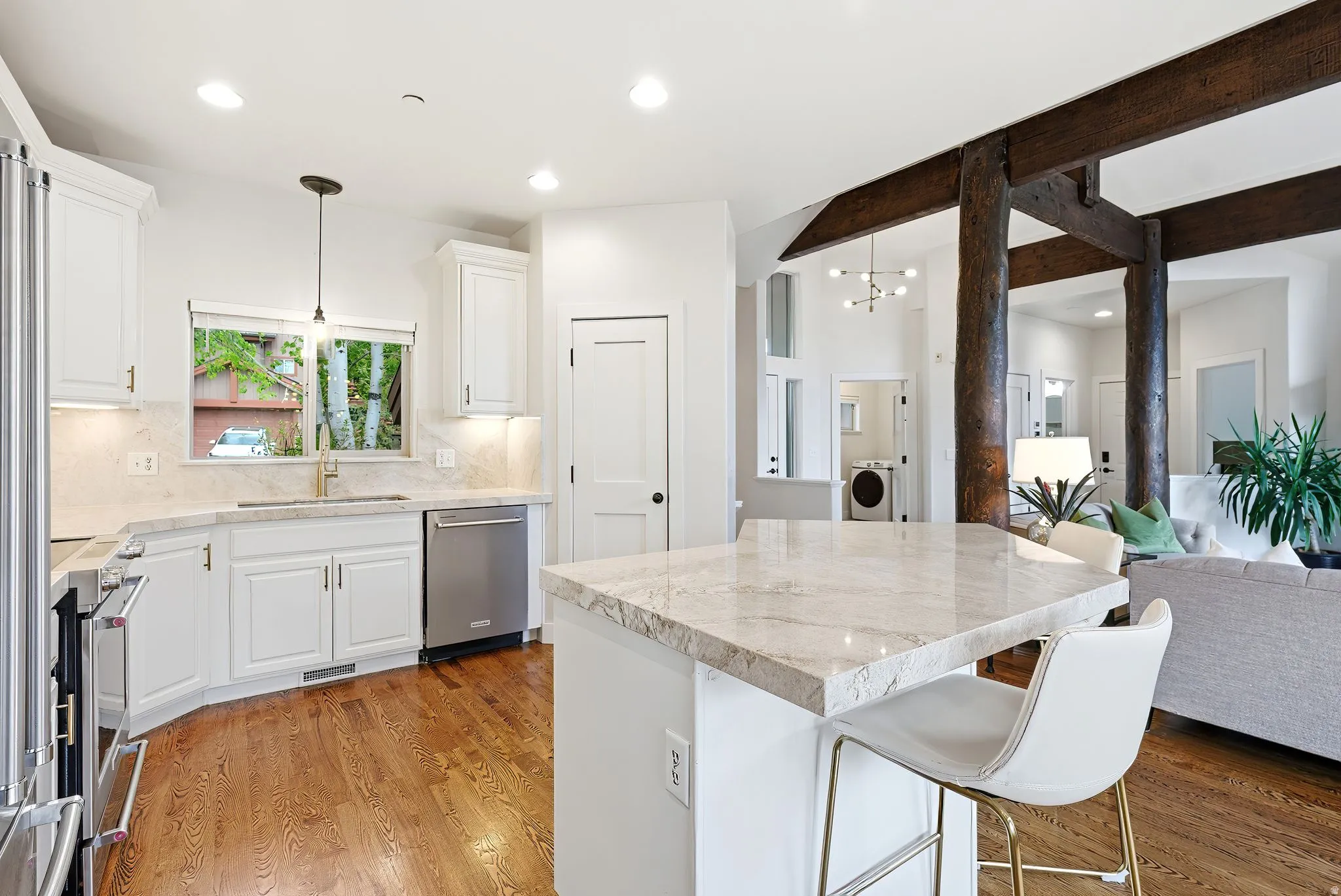 Open-concept kitchen featuring white shaker cabinetry, stainless steel appliances, and wood-finish flooring