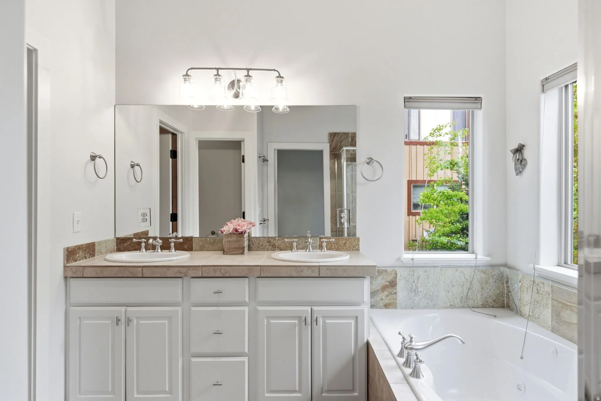 Bathroom featuring a double vanity with white cabinetry, tile countertops, and integrated sinks