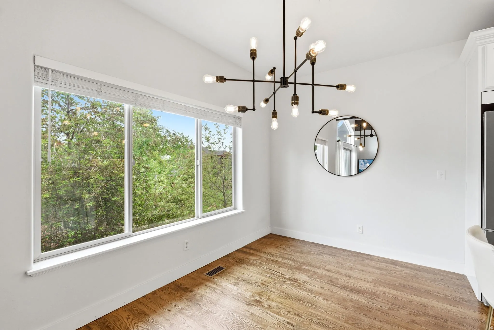 Spacious room featuring wood-finish flooring, a contemporary chandelier, and expansive windows