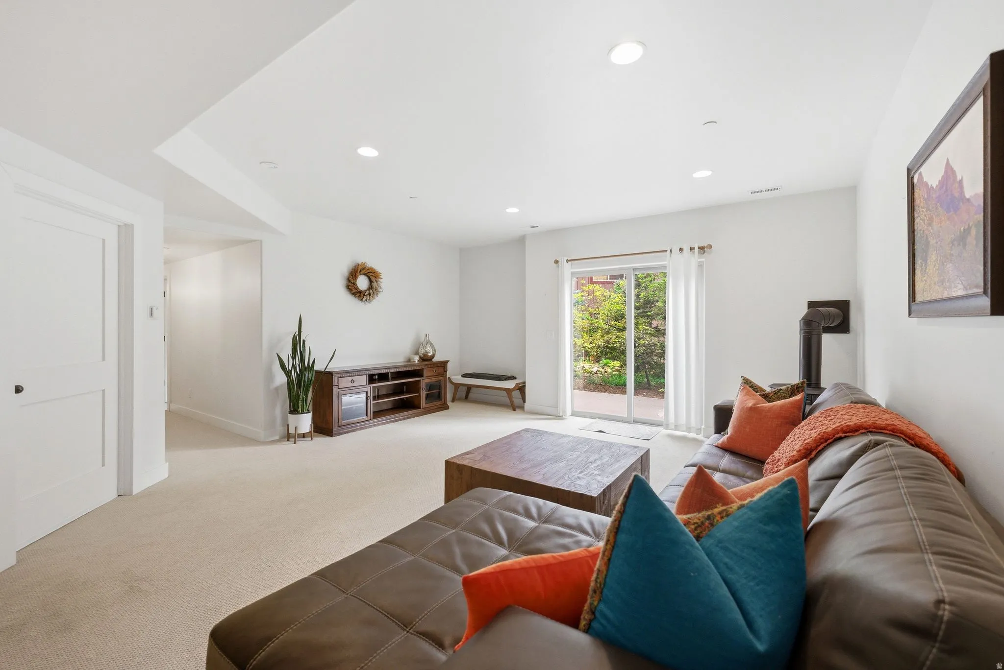 Spacious living area featuring light-toned carpeting and a sliding glass door leading to an outdoor space