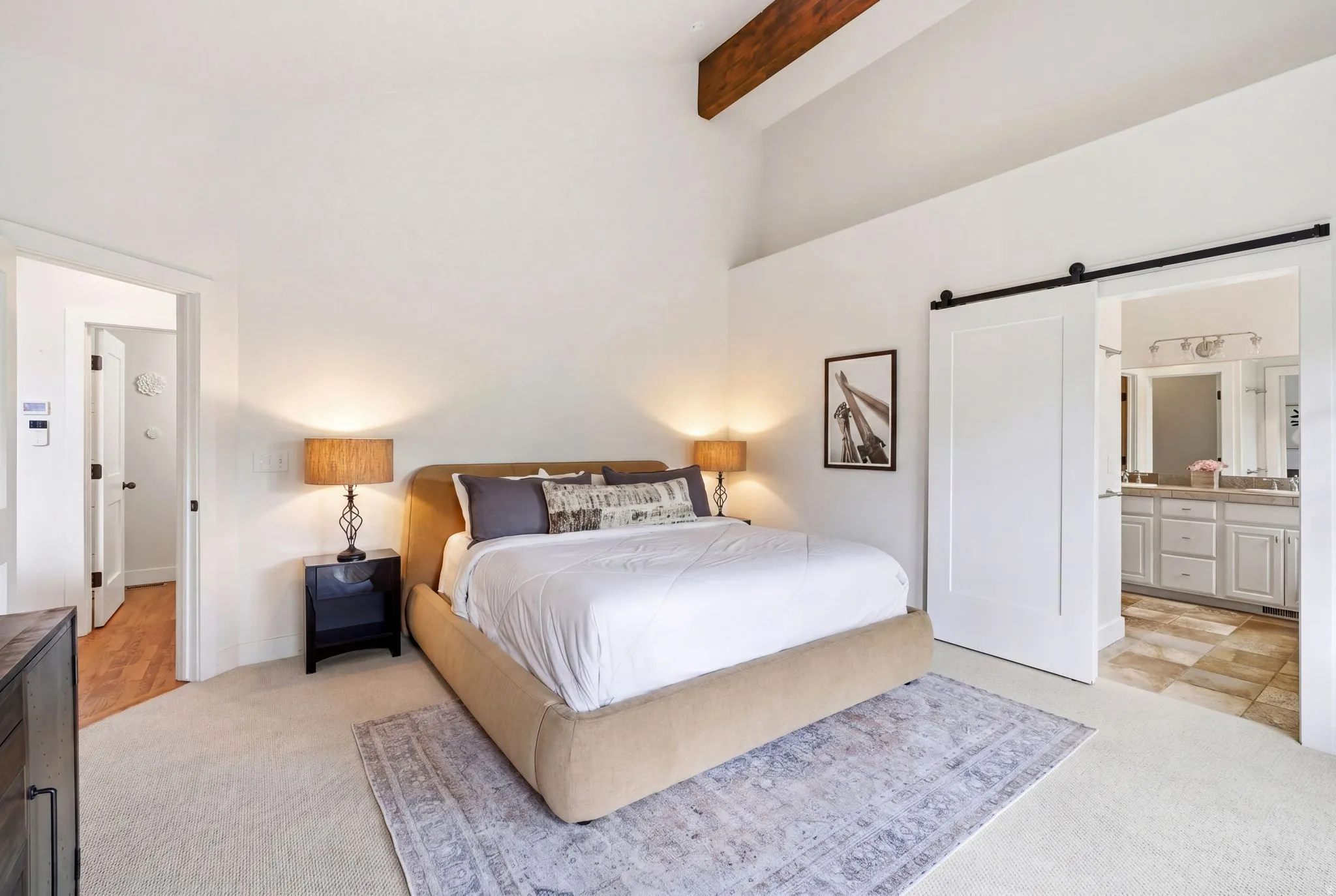 Vaulted ceiling with exposed wood beam and light-toned carpeting