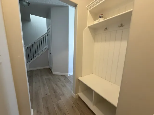 Built-in entryway bench with upper and lower shelving, coat hooks, and beadboard paneling