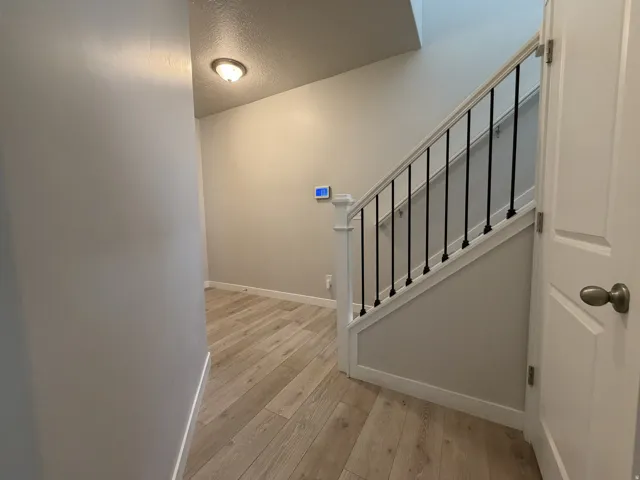 Staircase featuring white newel posts, black metal balusters, and wood-finish flooring