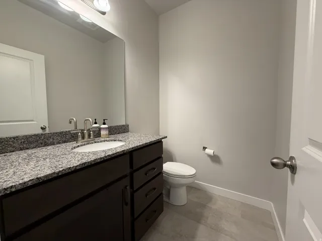 Bathroom featuring a dark wood-finish vanity with an undermount sink, a speckled stone countertop, a large wall mirror, and modern brushed nickel fixtures