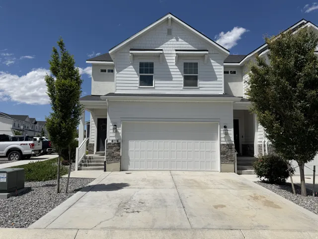 Modern townhome exterior featuring white horizontal siding and stone veneer accents