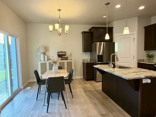 Open-concept kitchen and dining area featuring wood-finish flooring, dark wood cabinetry, and a sliding glass door