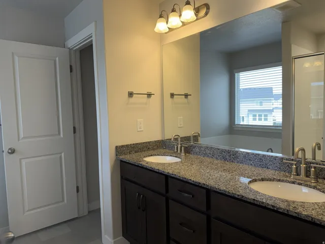 Dual vanity featuring a granite countertop, undermount sinks, and dark wood cabinetry
